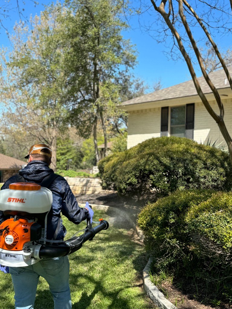 Technician treating shrubs with a backpack sprayer